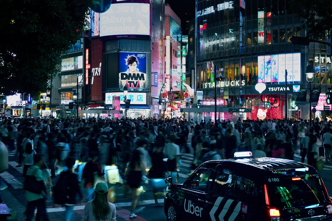 Crowded Shibuya Crossing in Tokyo illuminated by neon lights at night.